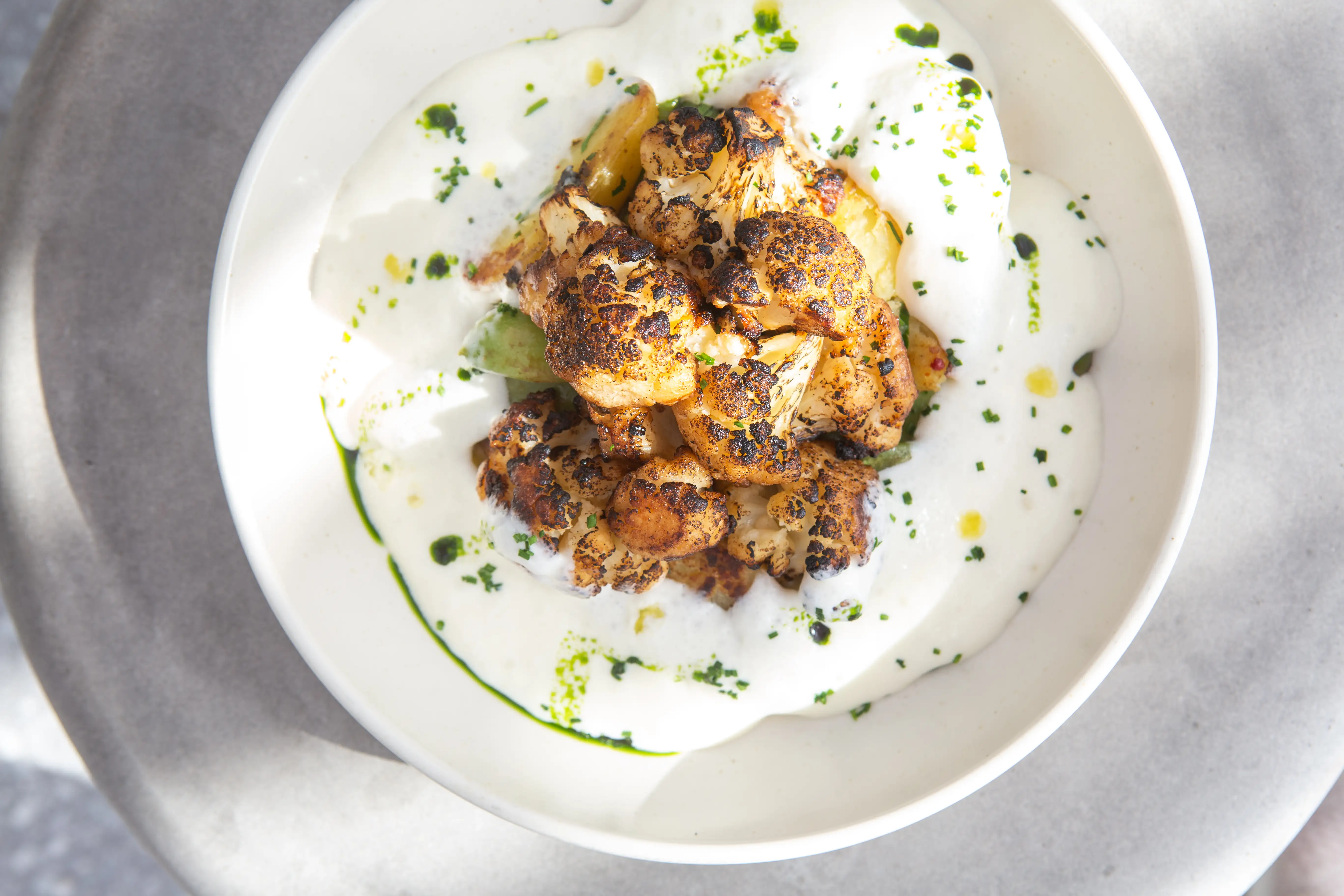 Charred cauliflower in creamy sauce with herb oil